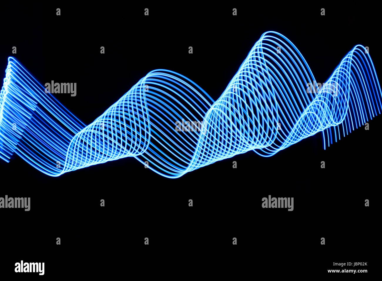 Blue Light Painting photography, ripples and swirls of electric blue parallel lines, against a black background Stock Photo