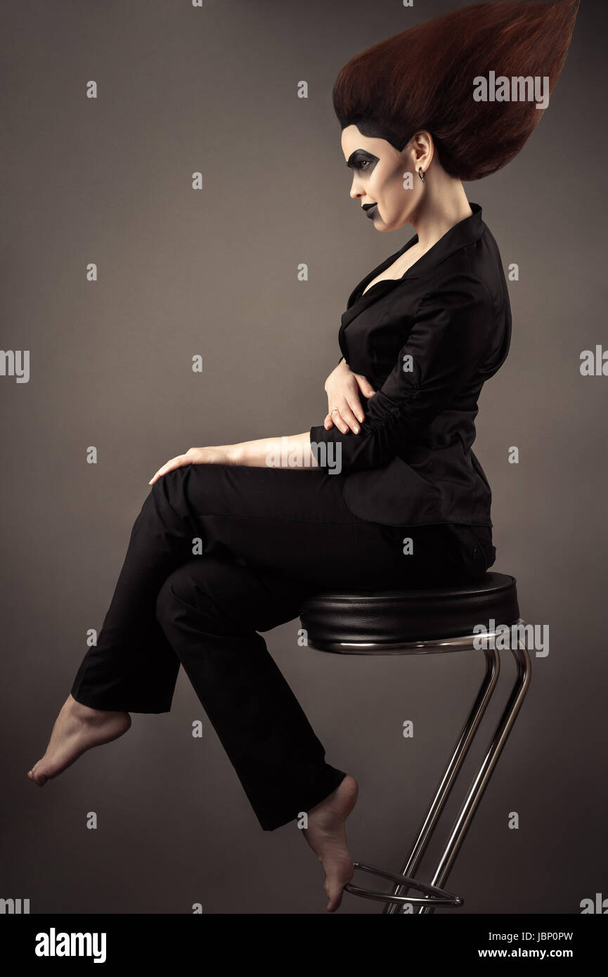 fashionable beautiful business woman sitting on bar stool with lush hair Stock Photo