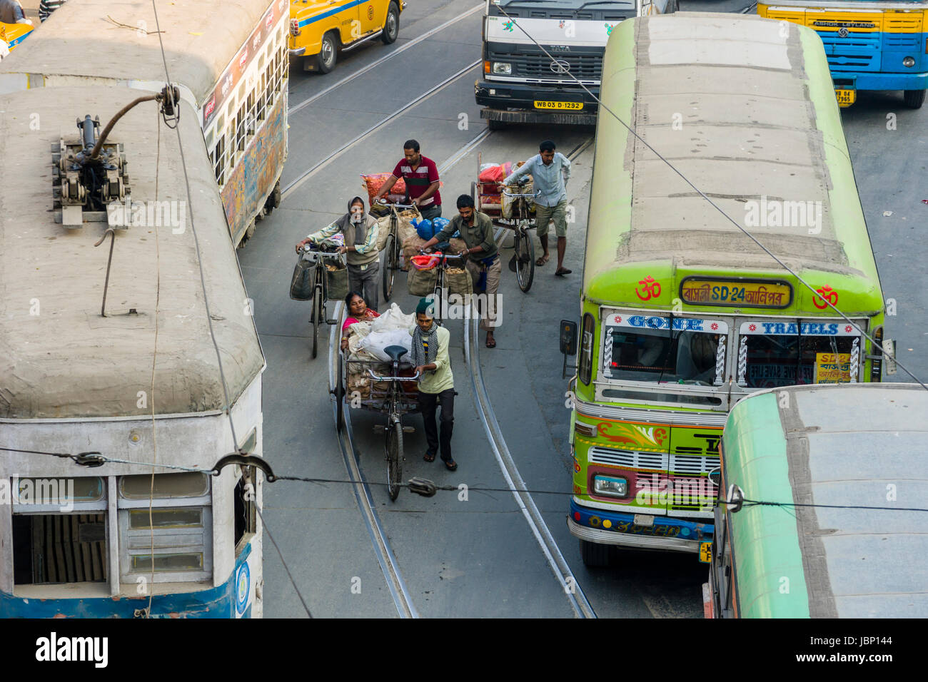 Cyclists between busses and a tram on a busy road in the suburb Sealdah Stock Photo