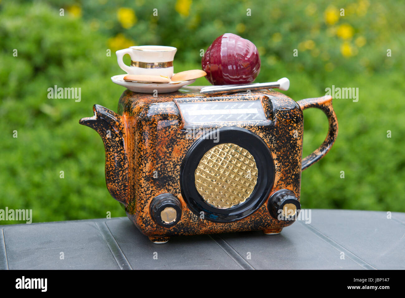 A novelty teapot in the shape of a radio with a cup of tea and biscuits and knitting needles and ball of wool. Stock Photo