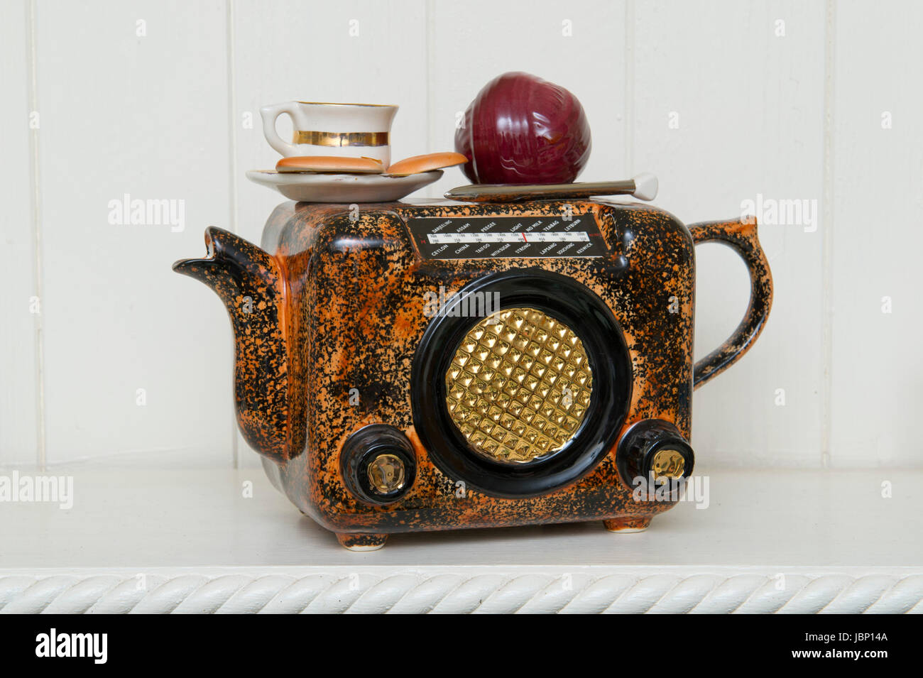 A novelty teapot in the shape of a radio with a cup of tea and biscuits and knitting needles and ball of wool. Stock Photo