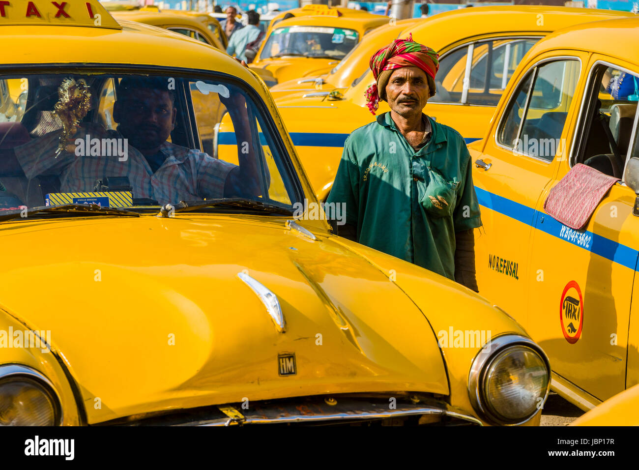 A taxi driver between yellow taxis, cabs, is waiting for customers
