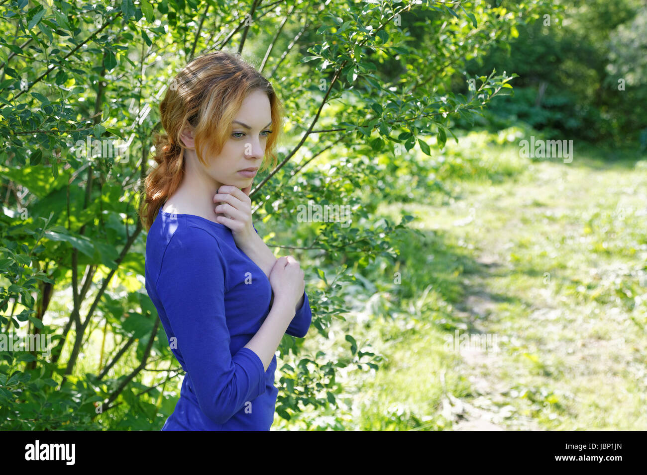 Thoughtful girl by the bush on a summer day Stock Photo