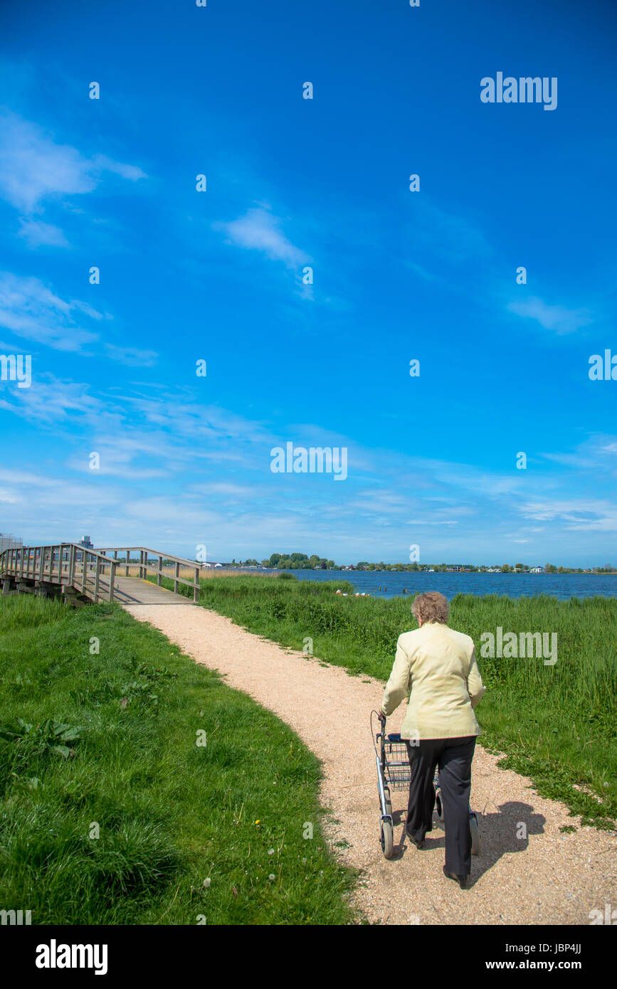 elderly woman walking with assist at footpath in the Netherlands Stock Photo