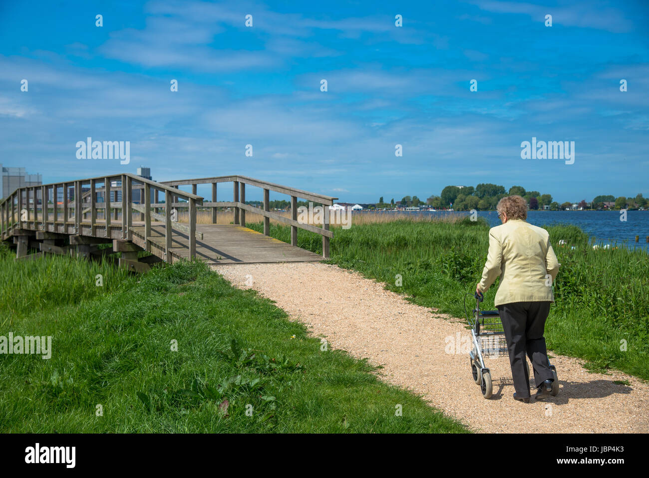 elderly woman walking with assist at footpath in the Netherlands Stock Photo