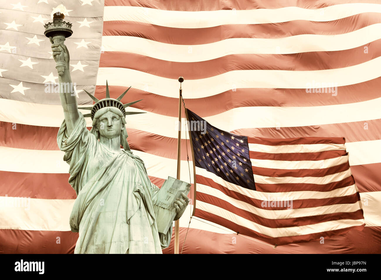 Statue of Liberty with two American flags. Large American flag in the background.Processed in subdued tones of color. Stock Photo