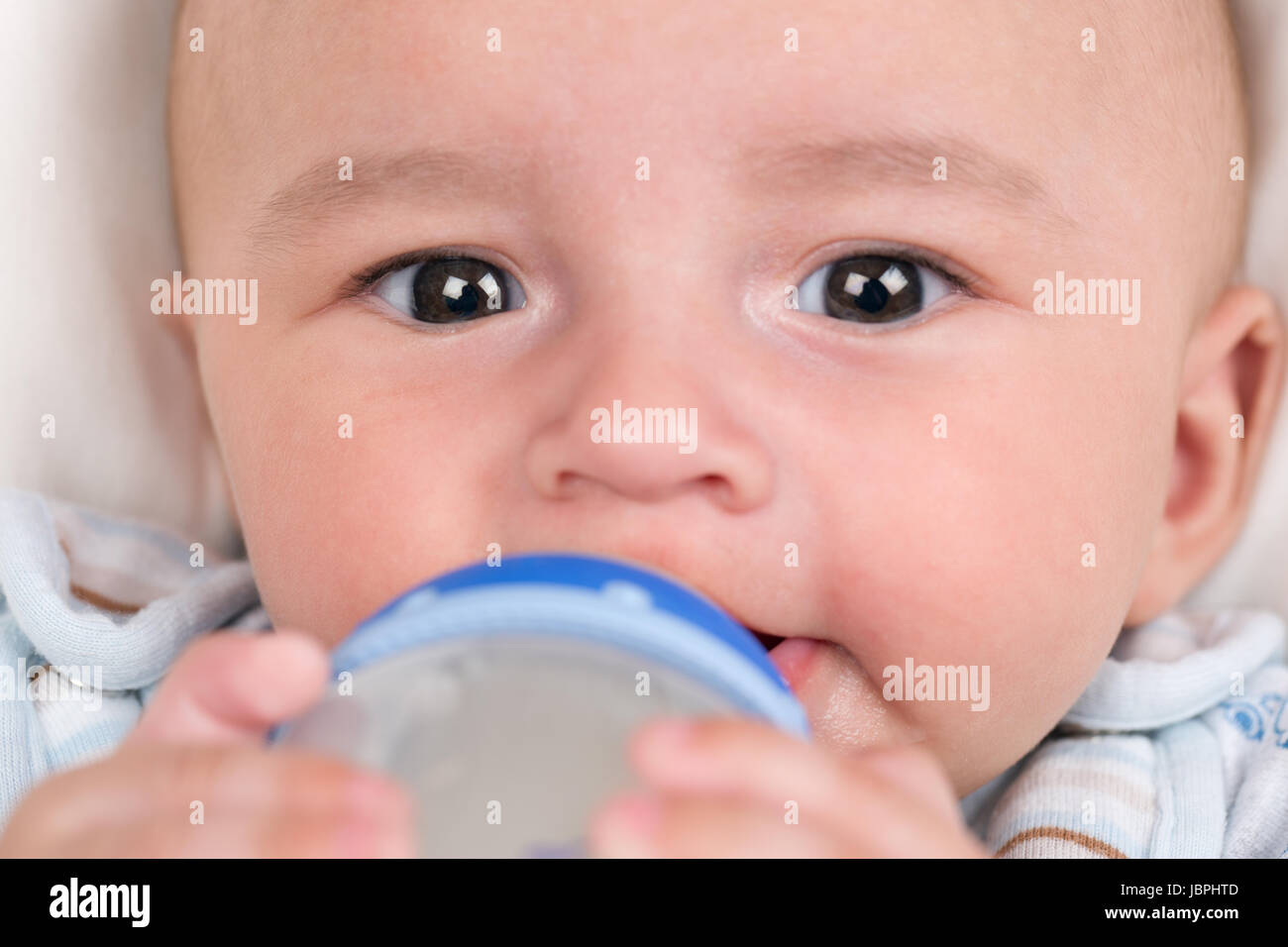Ein kleines Baby trinkt Milch und hält die Flasche Stock Photo