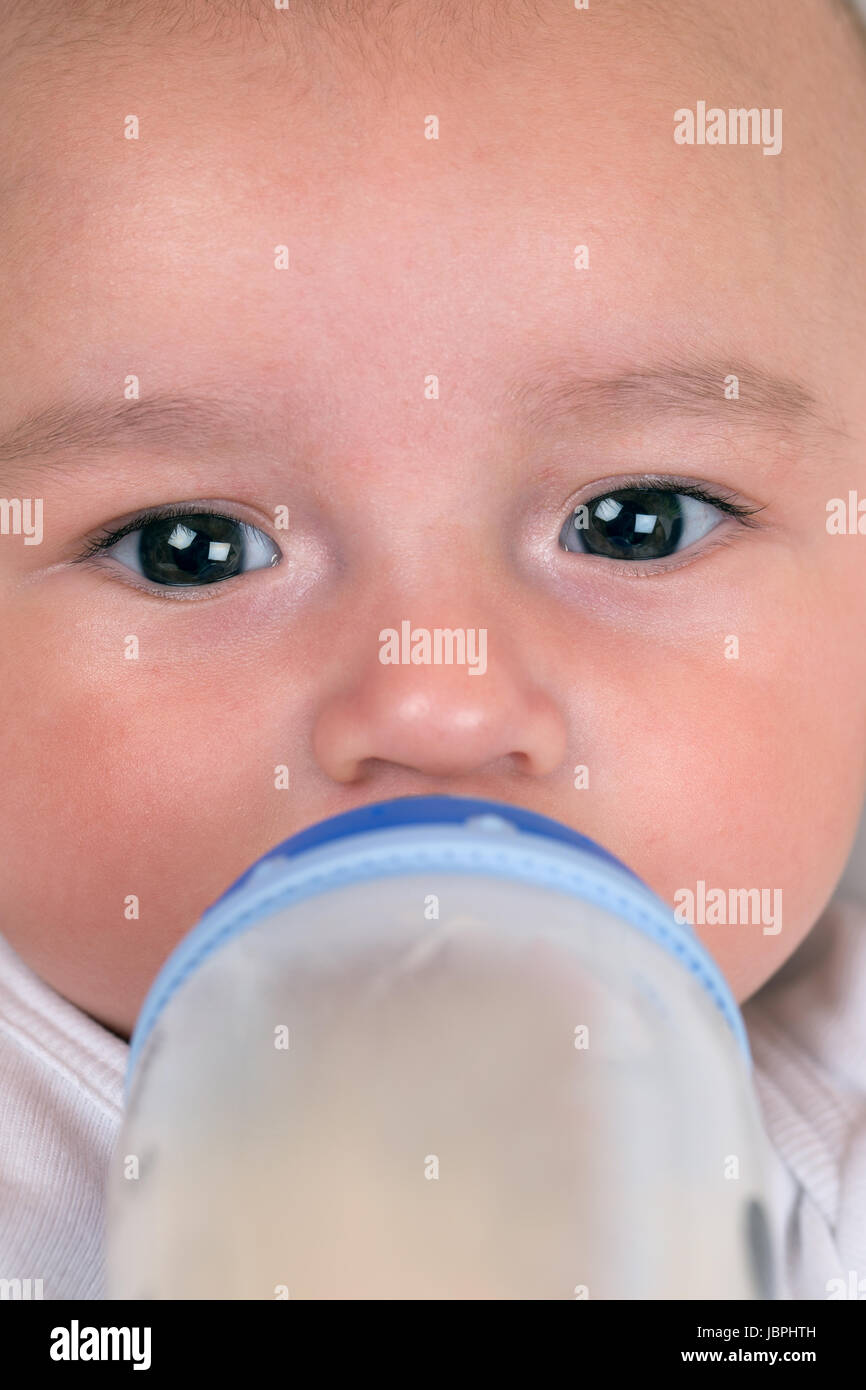 Ein kleines Baby hat Hunger und trinkt Milch aus einem Fläschchen Stock Photo