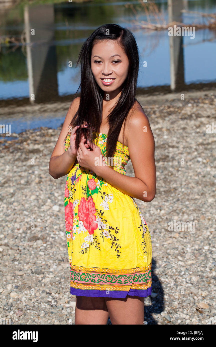 Oriental Woman Standing In Yellow Dress Outdoors Stock Photo