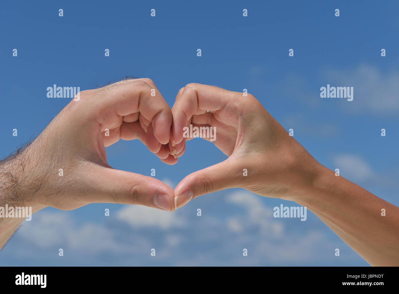 romantic couple make heart shape symbol of love with arms on sunny tropical  beach and sea in background Stock Photo - Alamy