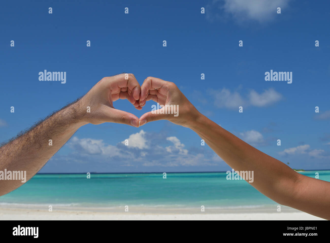 romantic couple make heart shape symbol of love with arms on sunny ...
