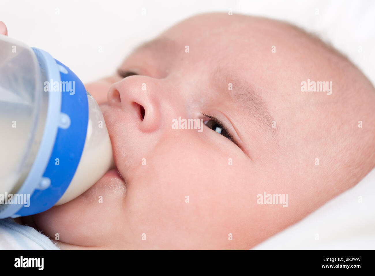 Ein kleines Baby hat Hunger und trinkt Milch aus einer Flasche Stock Photo