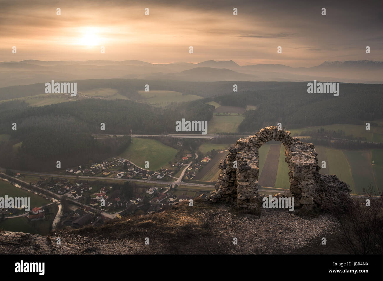 Ancient Ruins on a Rockface in Gleissenfeld, Austria with Mountains and Village in Background. Located in Nature Park Seebenstein-Turkensturz. Stock Photo