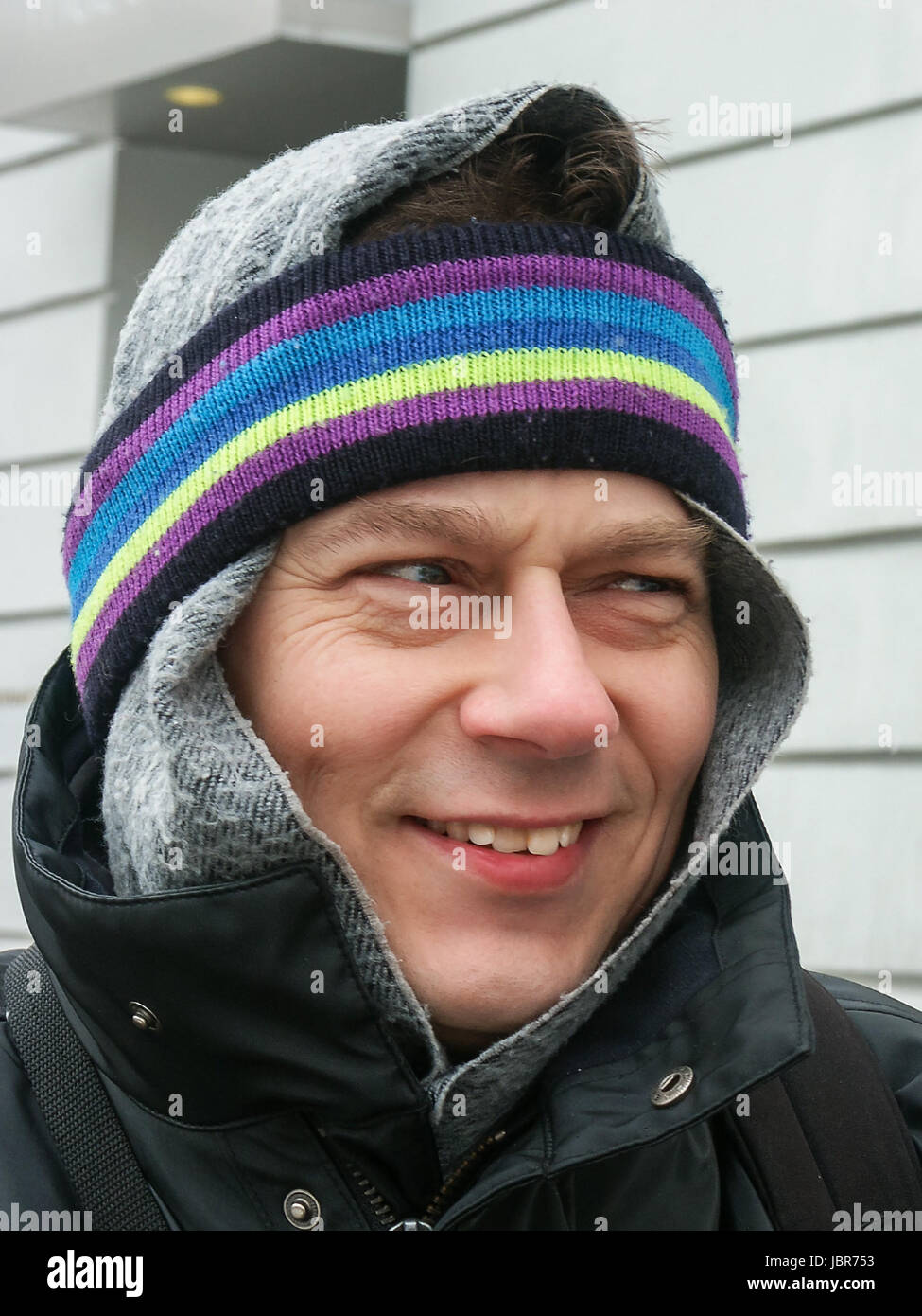 Portrait eines lächelnden Mannes in Winterbekleidung mit Schal und Stirnband auf dem Kopf Stock Photo