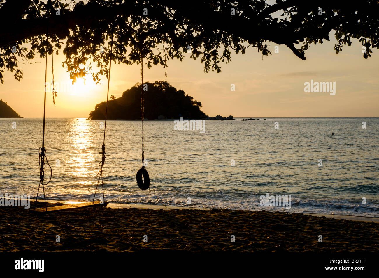 A swing and a tyre swing at sunset on Teluk Nipah Beach, Pangkor Island (Pulau Pangkor), off the West Malaysia coast. Stock Photo