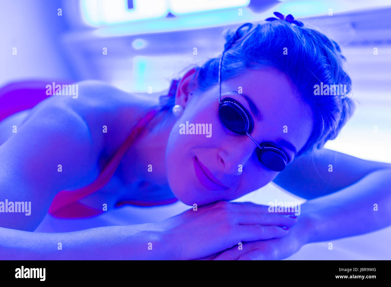 Woman in bikini tanning in wellness spa solarium Stock Photo