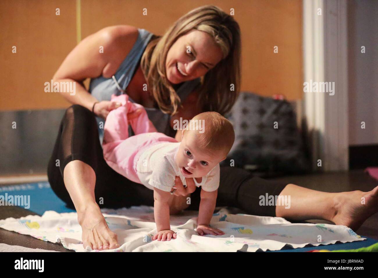 June 12, 2017 - Florida, U.S. - Eight-month-old Emily Rasquin of West Palm Beach participates in an Itsy Bitsy Yoga class at the Mandel Public Library of West Palm Beach Monday, June 12, 2017. ''The interaction is great, and it is good for motor development, '' said her mother Amy. According to teacher Kayla Willson of Jupiter, the classes help babies sleep better, digest better, and grow stronger. ''It encourages neuromuscular development and benefits bonding, digestion, sleep, and calm, '' she said. ''They sleep really well after class, which is great for the parents.'' Over the summer, the  Stock Photo