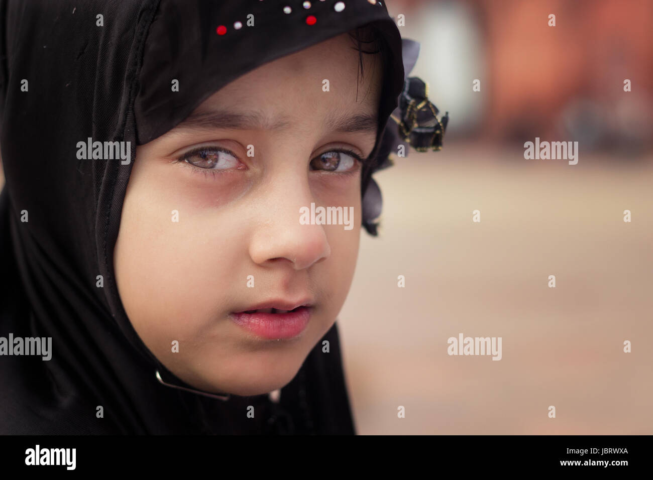 NEW DELHI, INDIA. MAY 31,2017: A young Muslim girl looks on as she along with her family sit in Jama Masjid.They are here to break their day long fast Stock Photo