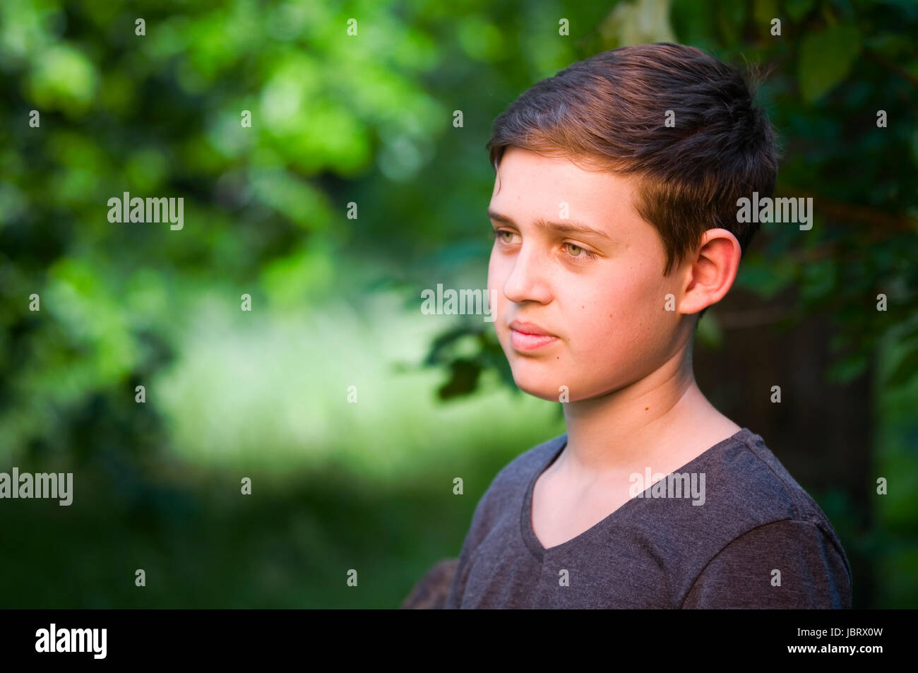 seitliches Outdoor-Kopf-und-Schulter-Porträt eines 13jährigen männlichen Teenagers zufrieden zur Seite blickend Stock Photo