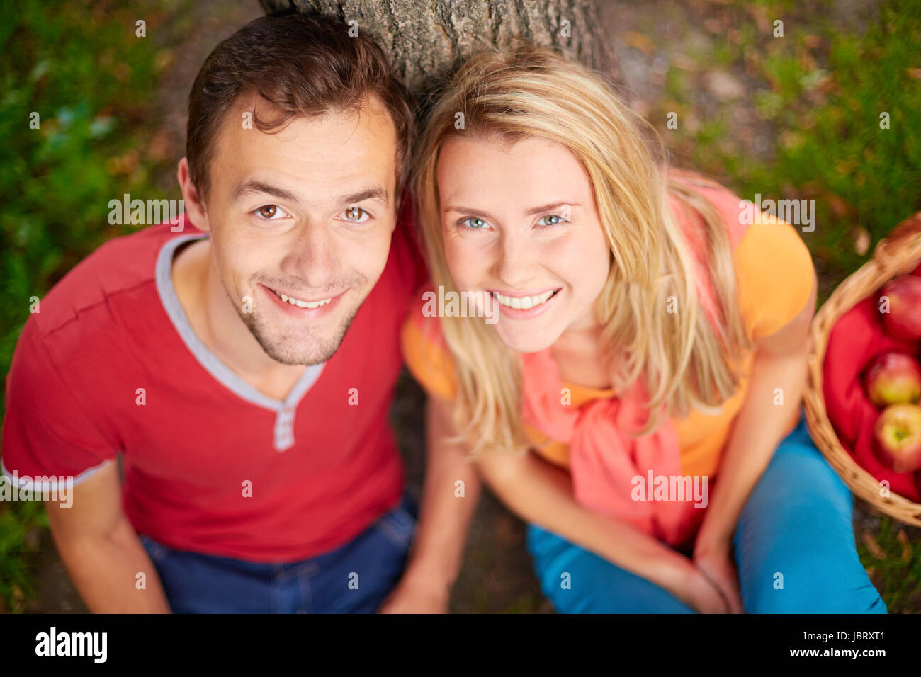 Happy young couple looking at camera in park Stock Photo - Alamy