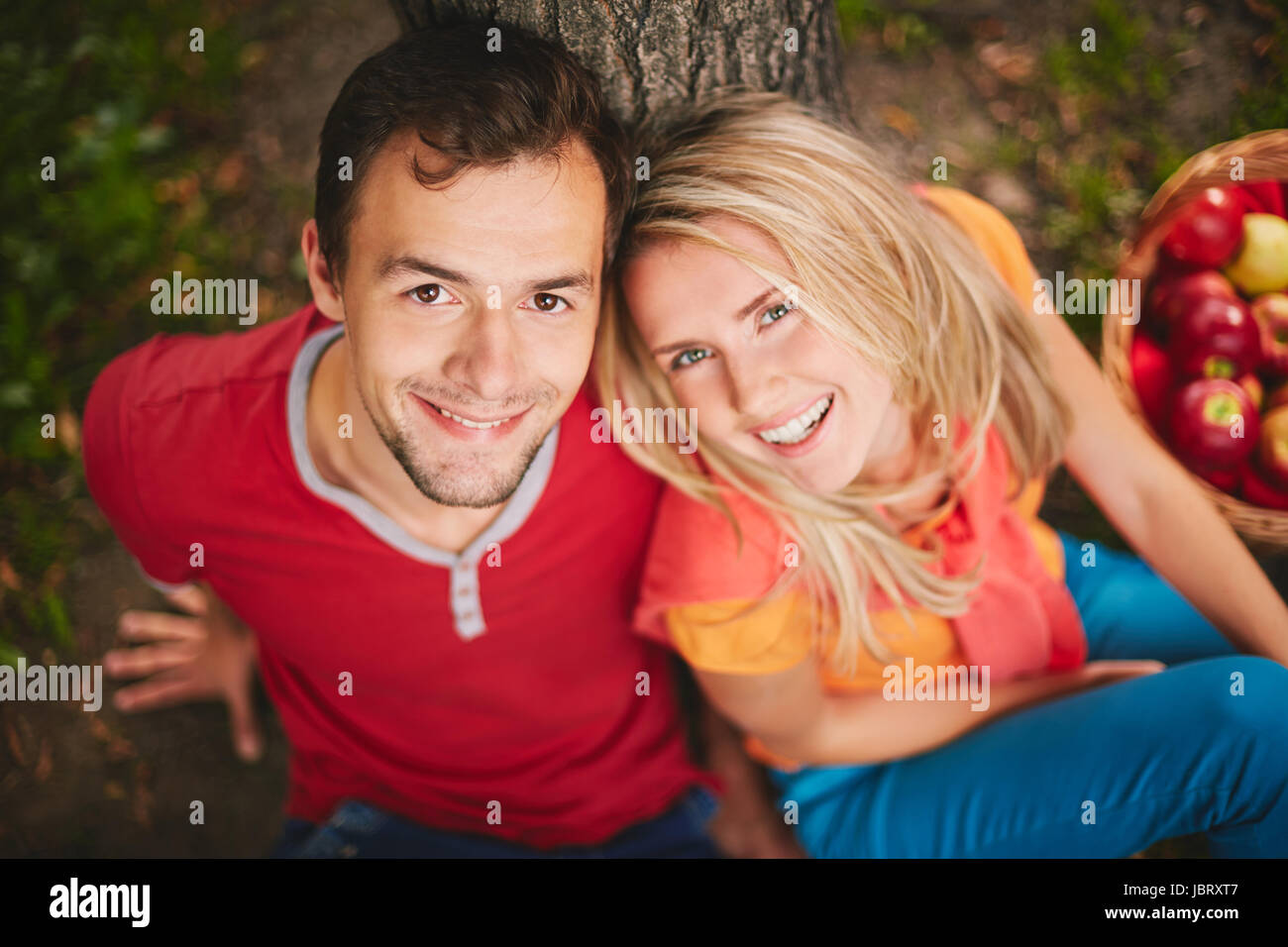 Happy young couple looking at camera in park Stock Photo - Alamy