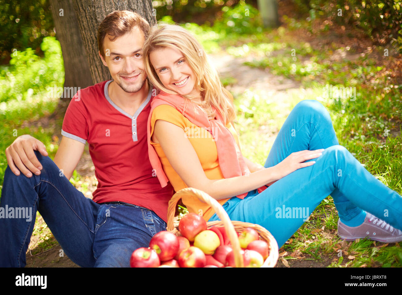 Happy young couple sitting in park and looking at camera Stock Photo ...
