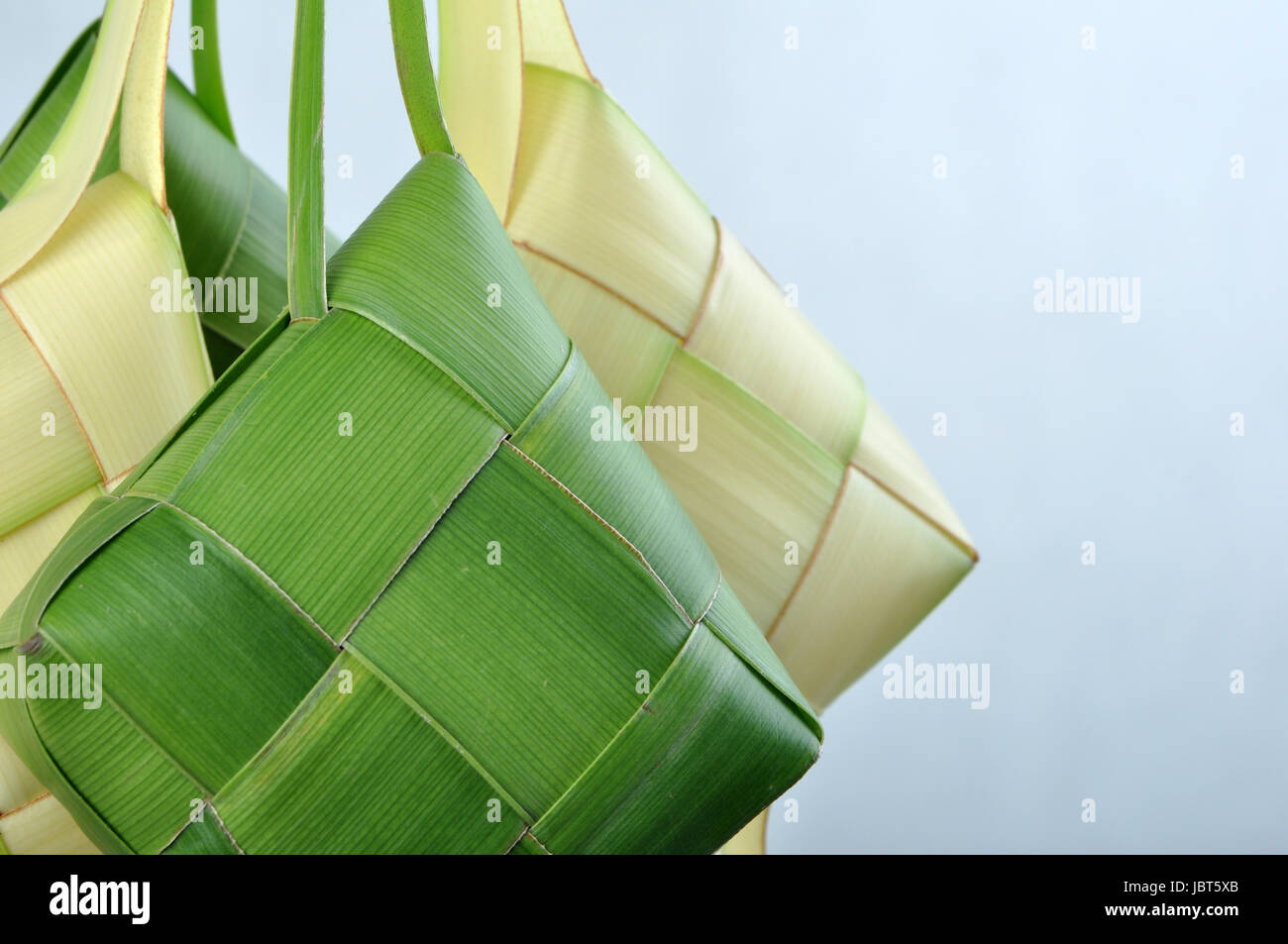 Ketupat, a type of dumpling made from rice packed inside a diamond-shaped container of woven palm leaf pouch. commonly found in Indonesia & Malaysia. Stock Photo