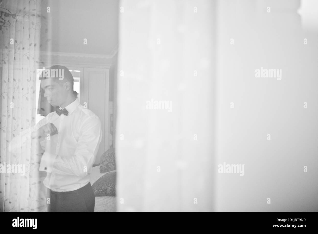 Handsome groom dressing up and getting ready for his wedding in the