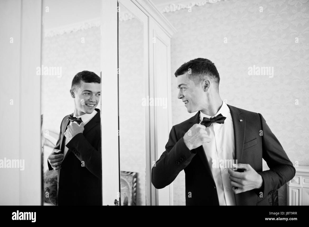 Handsome groom dressing up and getting ready for his wedding in the