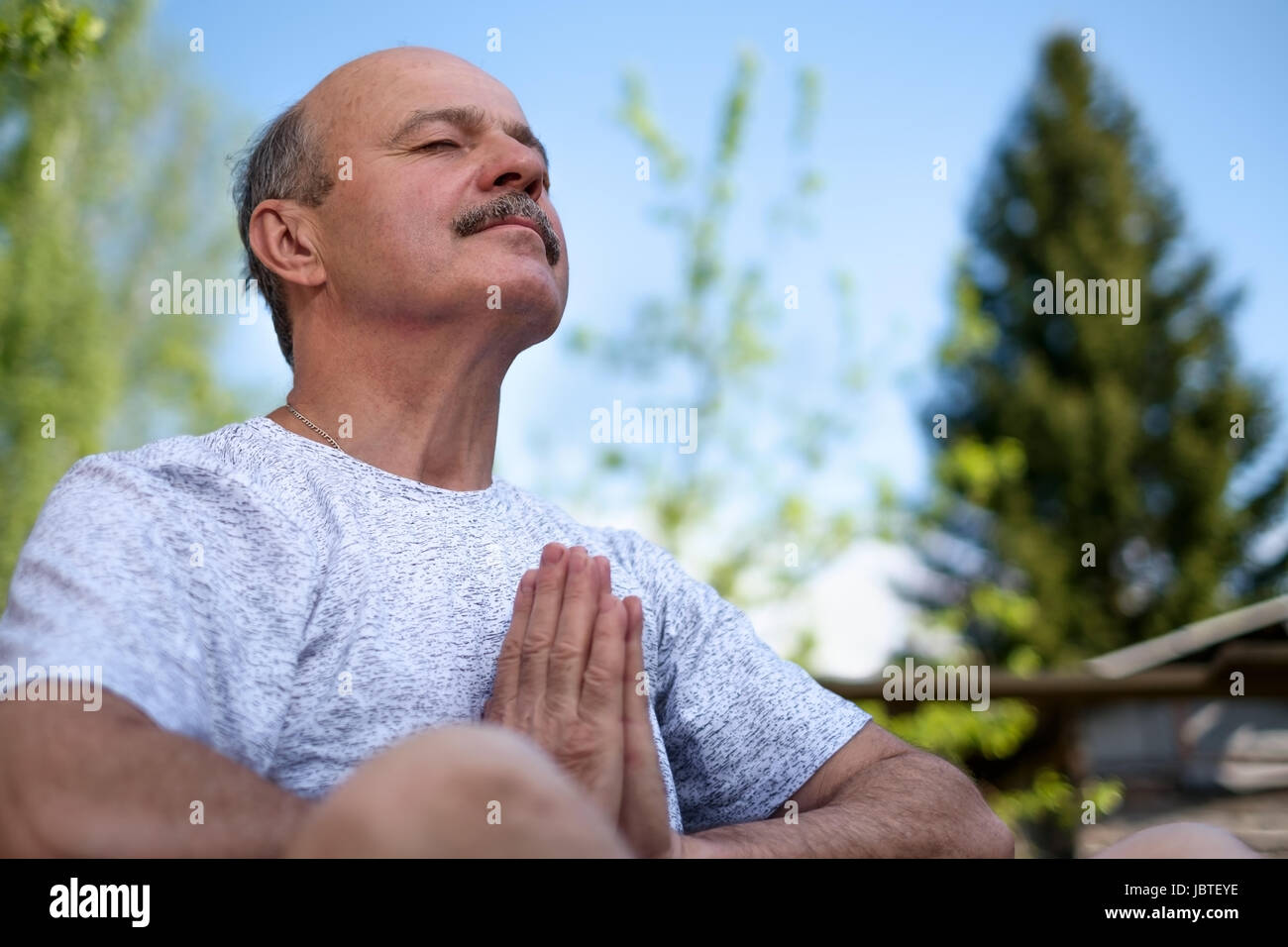 Senior man with mustache with namaste sitting.Concept of calm and meditation. Stock Photo