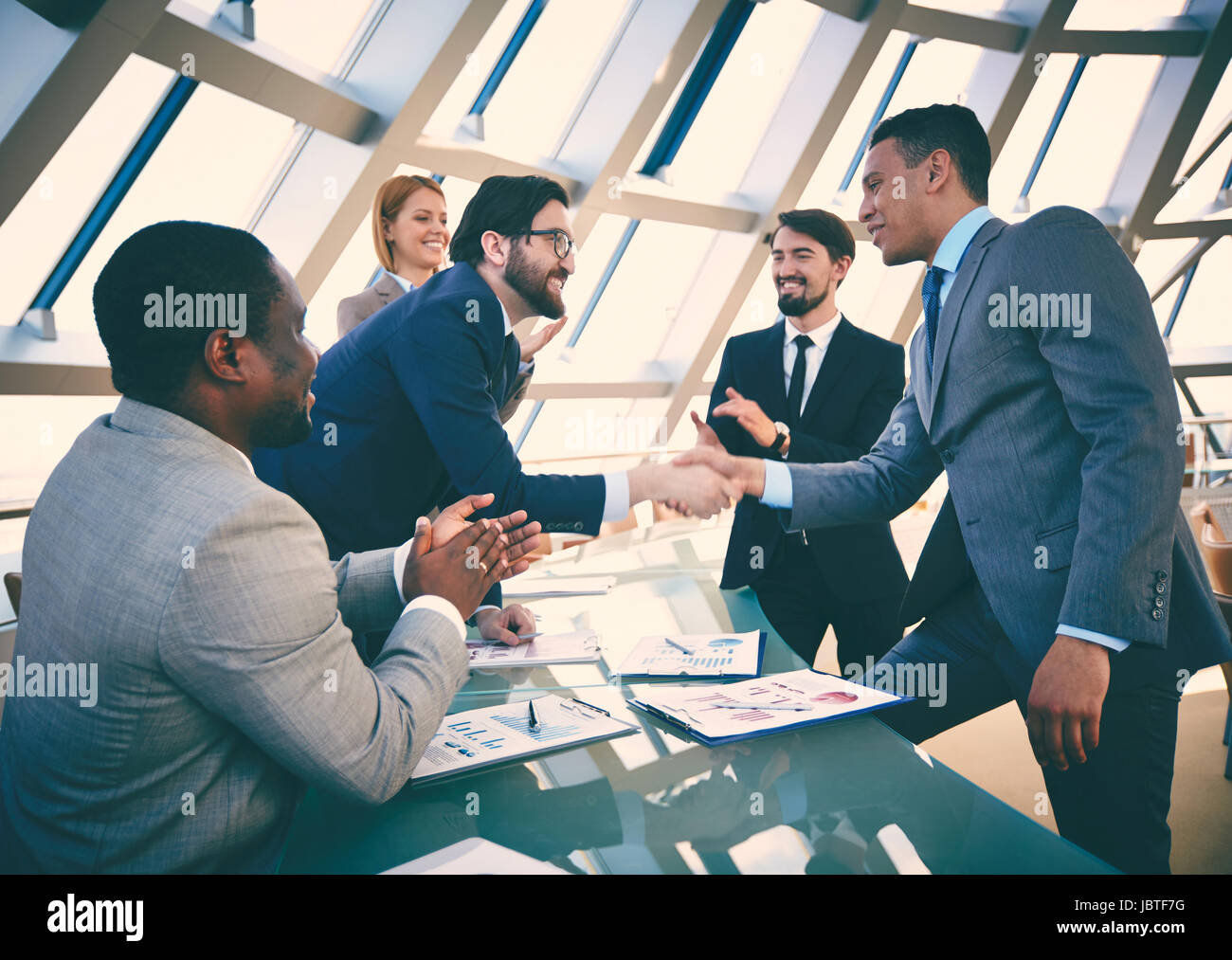 Group of business people congratulating their colleagues with striking grand deal Stock Photo