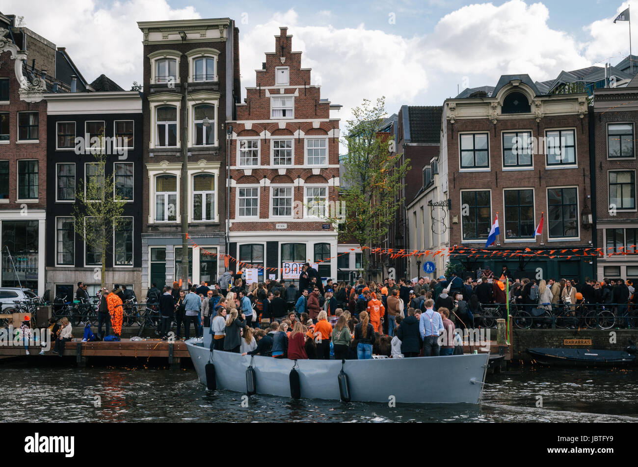 Amsterdam, Netherlands - 25 April, 2017: Local people and tourists dressed in orange clothes ride on boats and participate in celebrating King's Day a Stock Photo