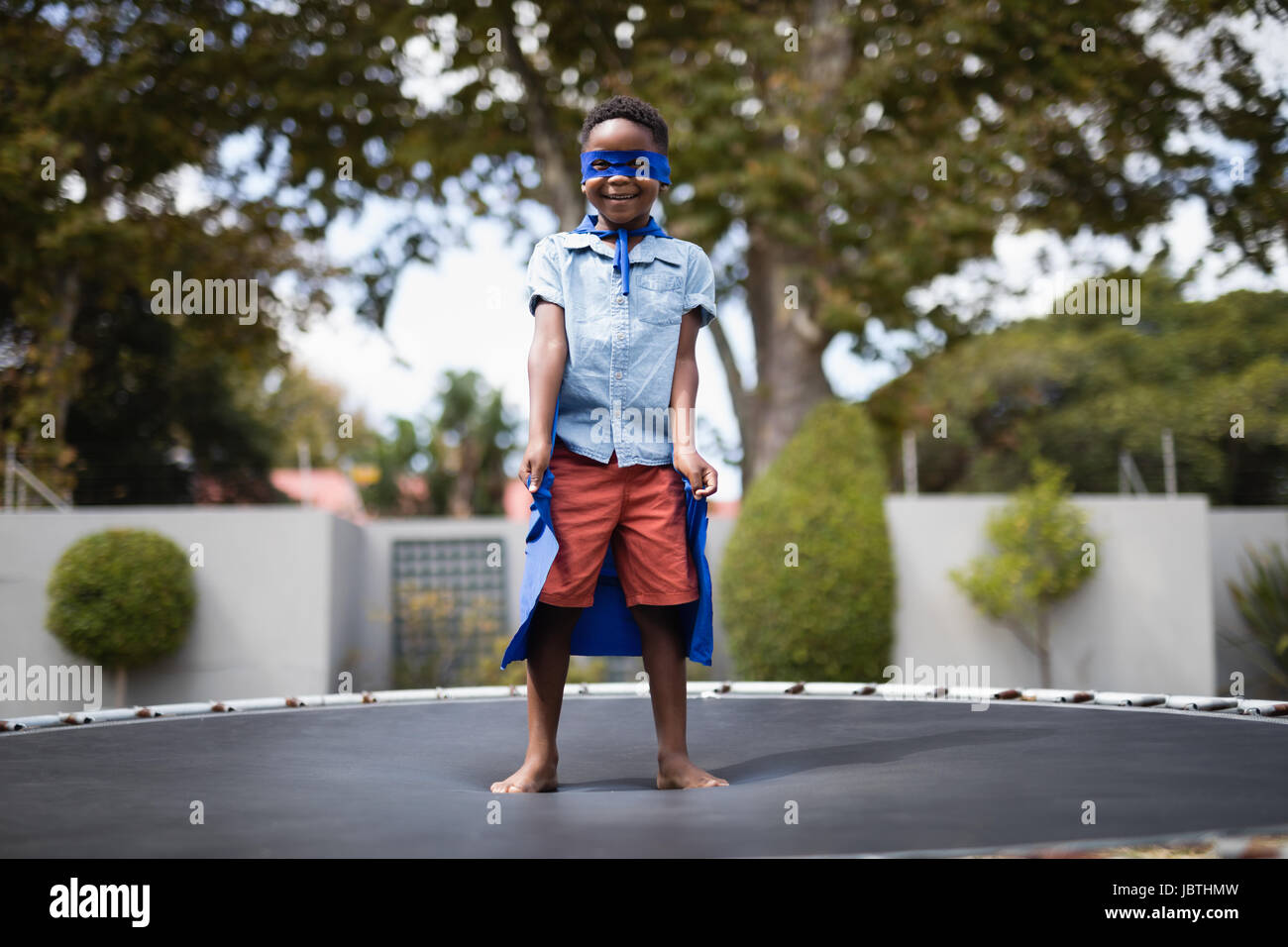 Full length of boy in superhero costume standing on trampoline Stock