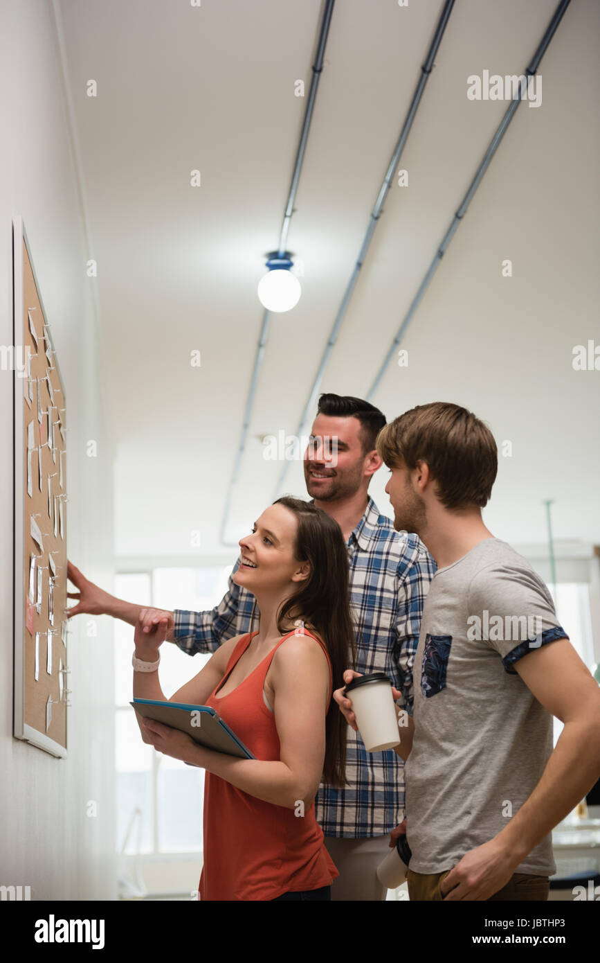 Executives discussing over bulletin board in office Stock Photo