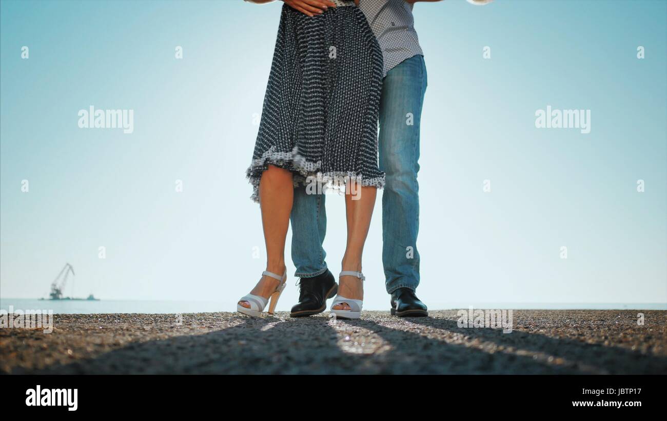 Young couple dancing latin music: Bachata, merengue, salsa. Two elegance pose on sea or ocean background. Woman in beautiful long dress. Stock Photo