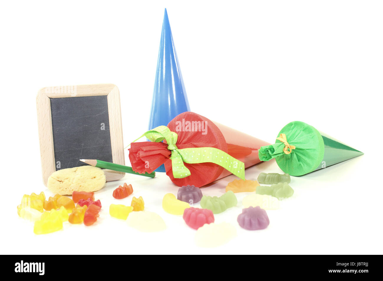 Schultüten mit Stift, Schwamm, Tafel und Süßigkeiten vor hellem Hintergrund Stock Photo
