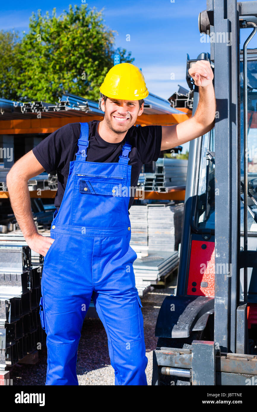 builder or driver with pallet transporter or lift fork truck on construction or building site Stock Photo