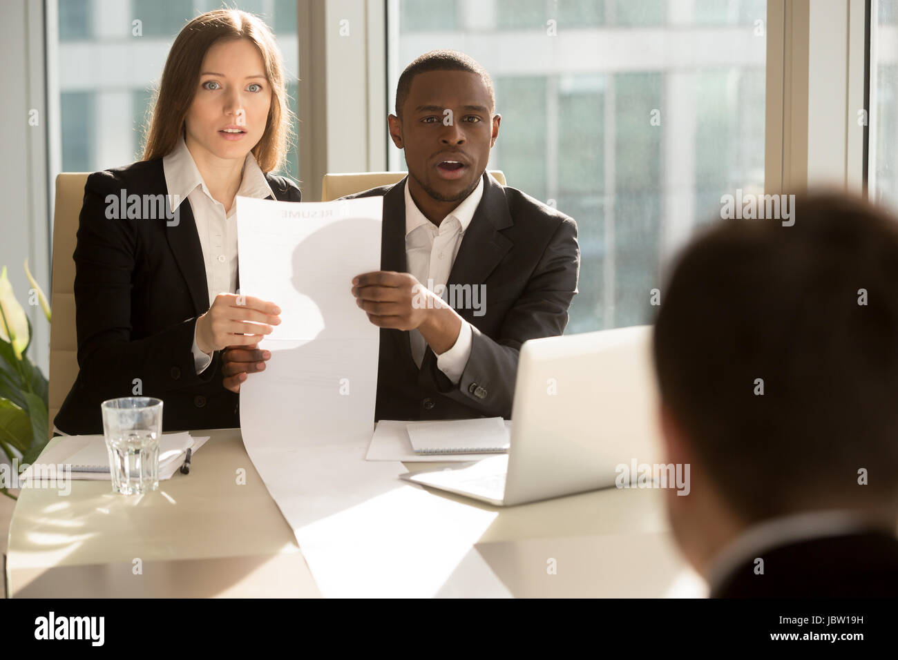 Multiracial recruiters holding - Multiracial Recruiters Holding Long Sheet Of Paper Looking Surprisingly JBW19H