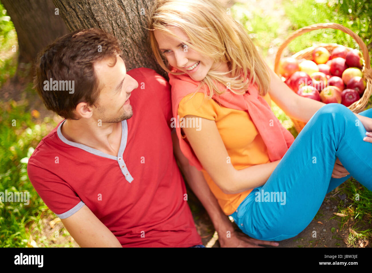 Happy young couple sitting in park and looking at one another Stock ...
