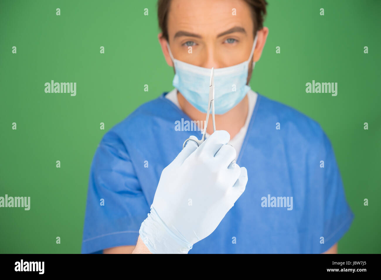 Male nurse or doctor wearing surgical scrubs and a mask holding up a ...