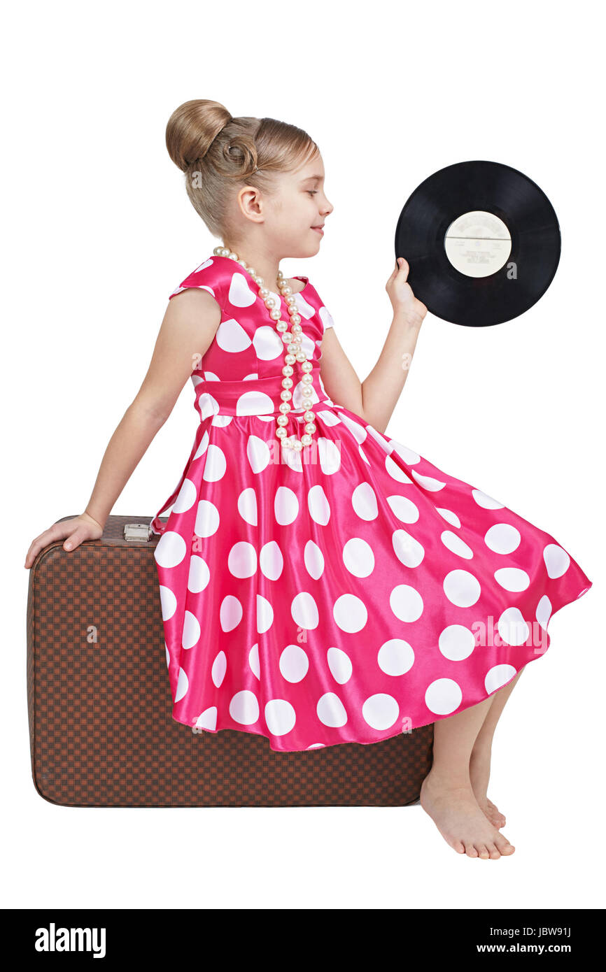 Dressed in a retro style girl sitting on old suitcase Stock Photo