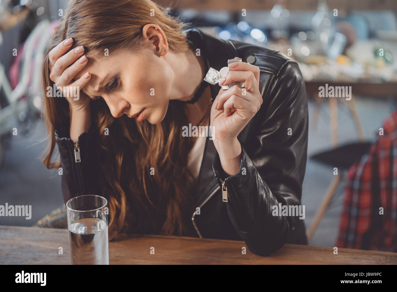 woman with hangover with medicines in messy room after party Stock Photo