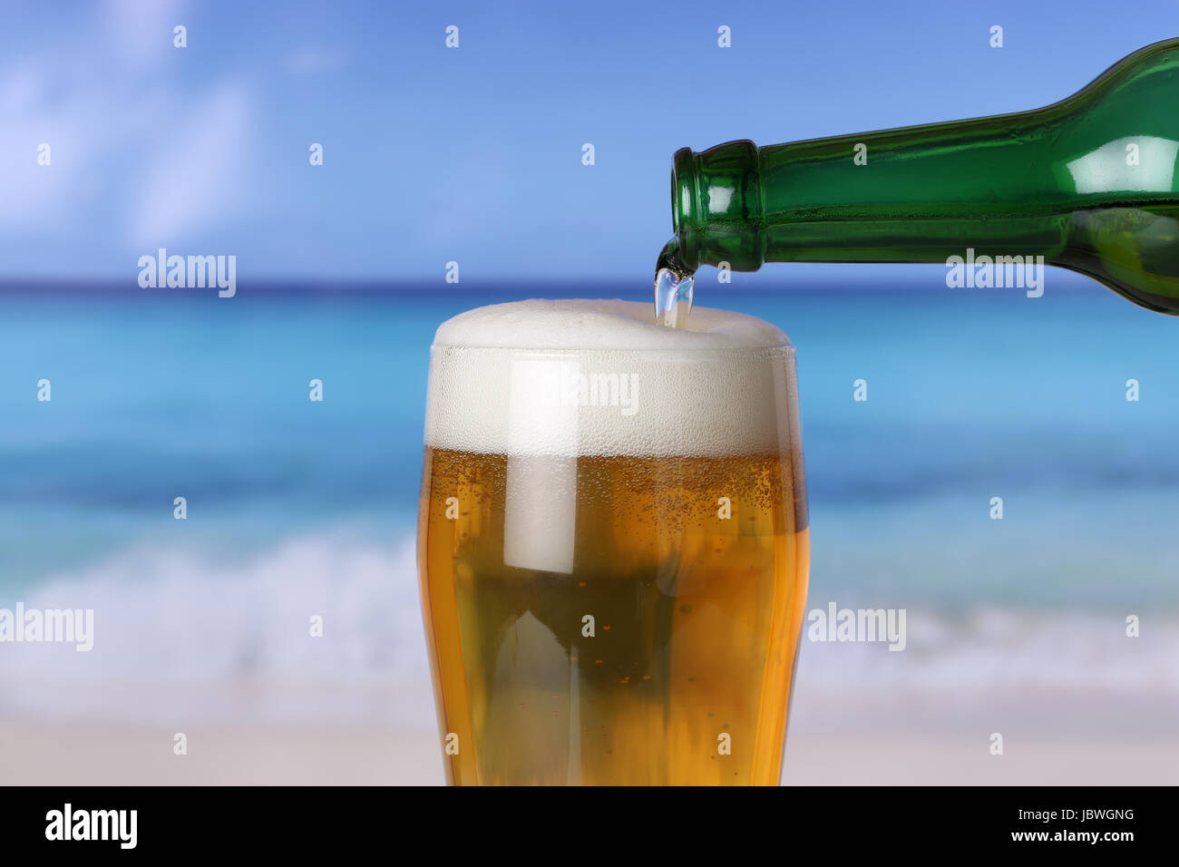 Bier eingießen aus einer Flasche ins Glas am Strand Stock Photo