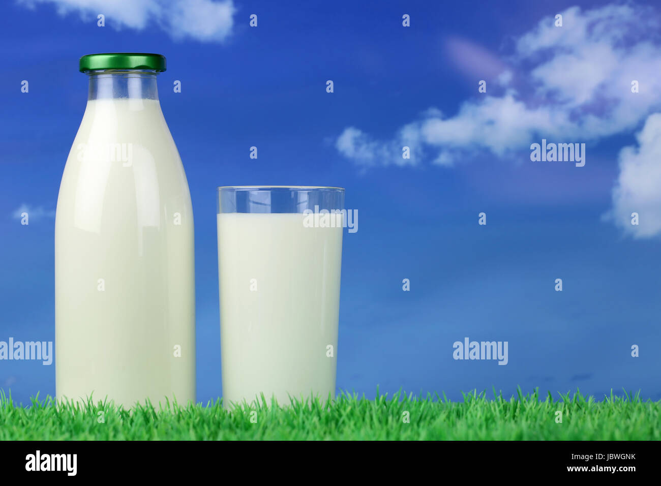 Frische Milch in der Flasche und im Glas auf einer Wiese mit Textfreiraum Stock Photo