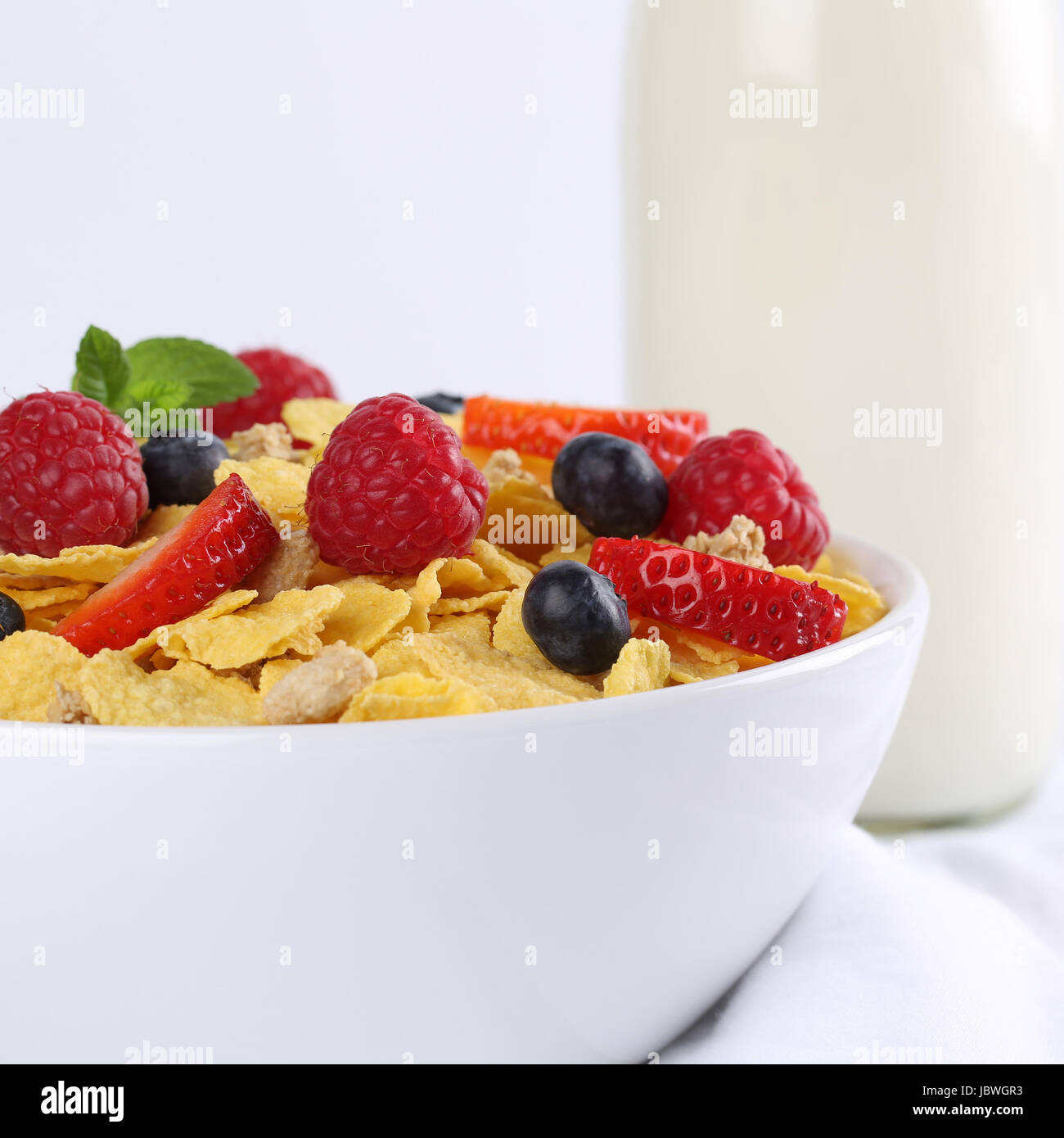 Frische Früchte wie Erdbeeren und Himbeeren mit Milch und Cornflakes ...