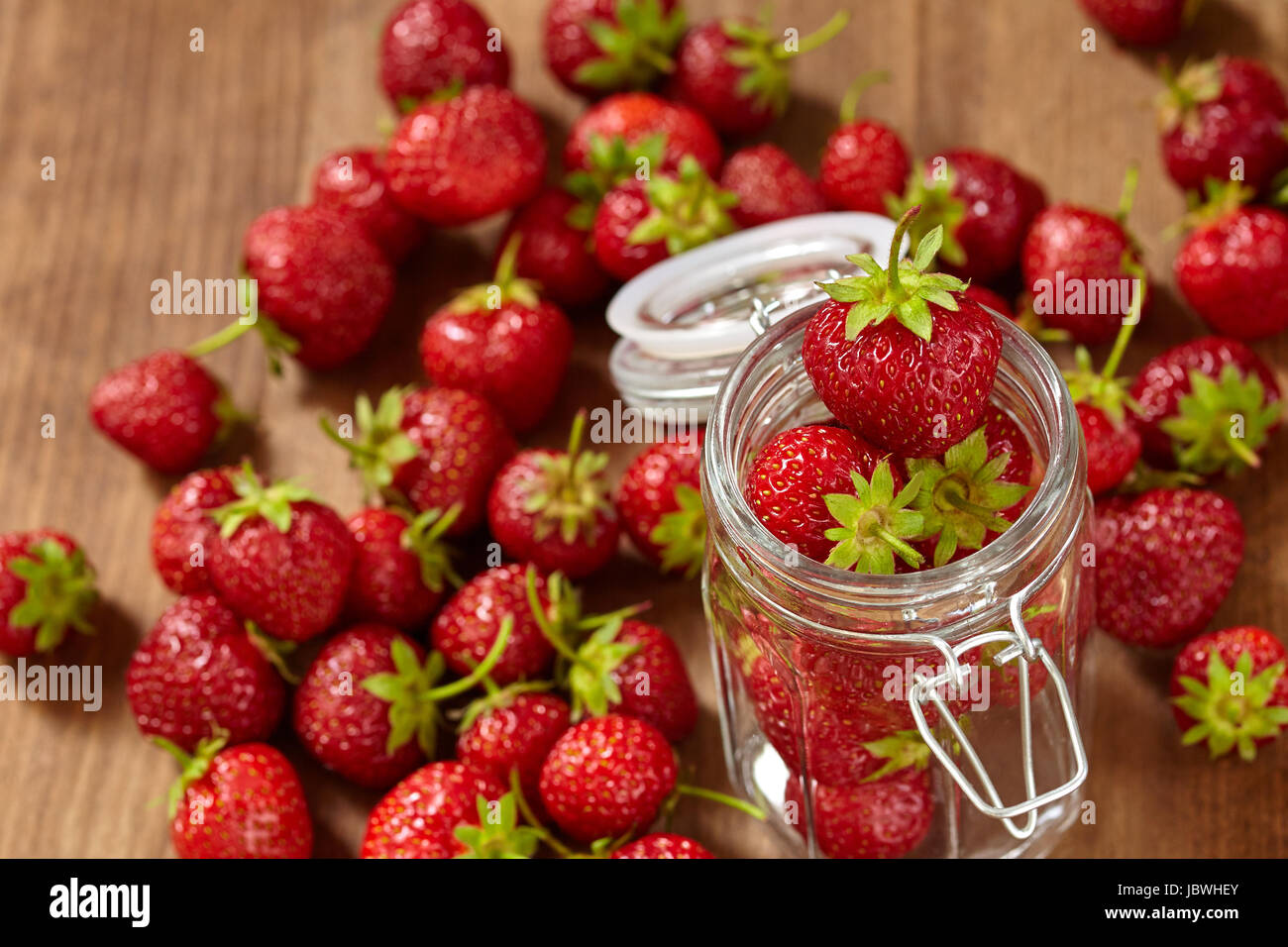 Fresh red strawberries for jam in a glass jar on the brown wooden table ...