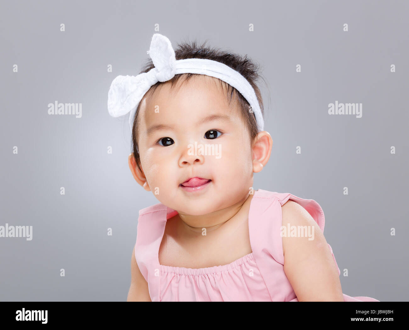 Adorable baby girl with lick sticking out Stock Photo - Alamy