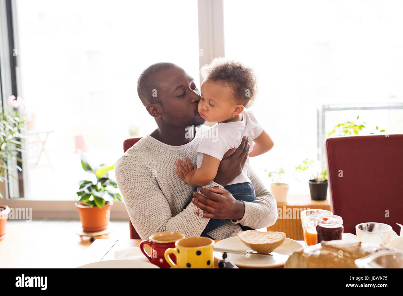 Young afro-american father with his daughter having breakfast. Stock Photo