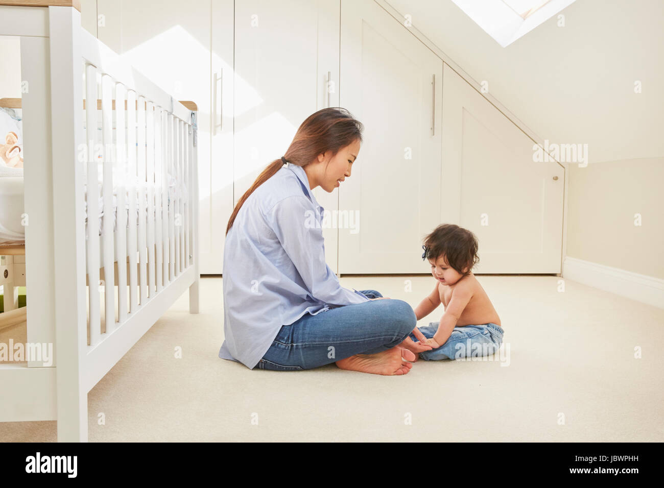 Woman sitting on floor playing with baby daughter Stock Photo - Alamy