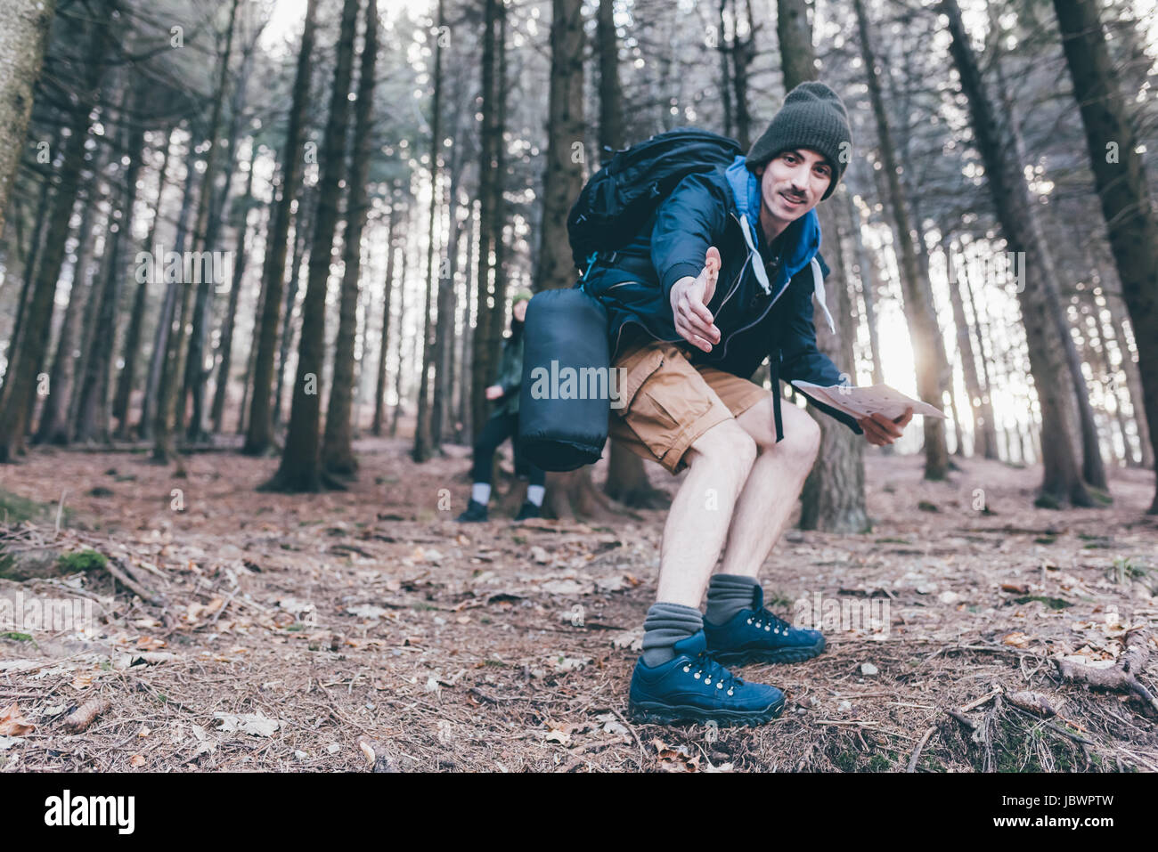 Man hiking in steep forest offering a helping hand, Monte San Primo, Italy Stock Photo
